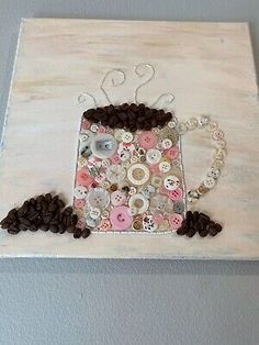 a coffee cup made out of buttons is hanging on the wall