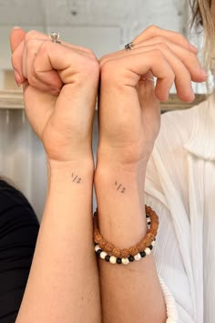 two people with matching tattoos on their arms and wristbands, both holding each other's hands