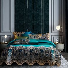 a bed with blue and gold comforters in a room next to two lamps on either side of the bed