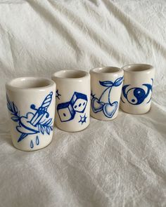 four blue and white ceramic cups sitting on top of a bed next to each other