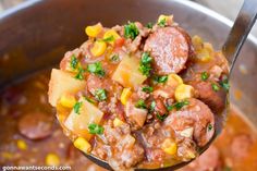 a spoon full of stew with corn and sausage