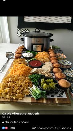 a table full of different types of food on top of a wooden cutting board next to a crock pot