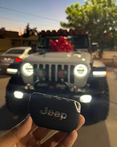 a jeep with its lights on is being held up by someone's hand in the street