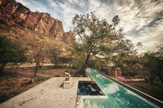 an outdoor swimming pool in the middle of a wooded area with trees and mountains behind it