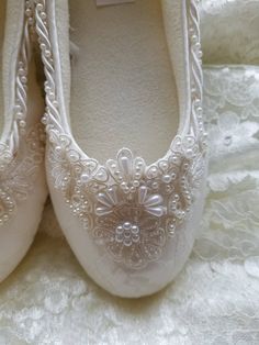 a pair of white wedding shoes with pearls on the bottom and lace trimmings