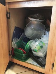 an open cabinet filled with plastic containers and dishes