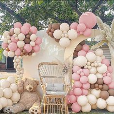 a teddy bear sitting in front of a giant balloon arch with balloons on it's sides