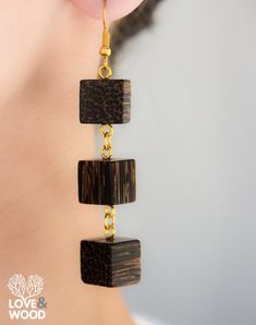 a woman wearing wooden earrings with chains hanging from it's ear ends and the back of her ear