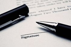 a pen sitting on top of a piece of paper with the word signature next to it