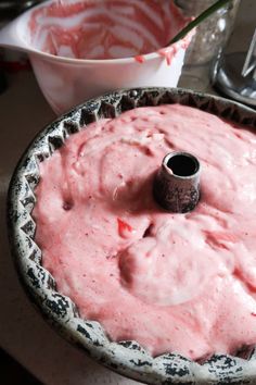 a cake pan filled with pink icing on top of a table