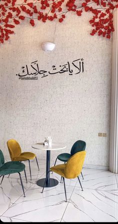 three chairs sitting at a table in front of a wall with arabic writing on it