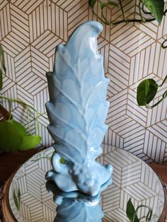 a blue vase sitting on top of a glass plate next to a potted plant