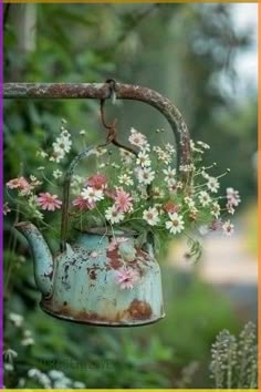 an old tea kettle with flowers in it