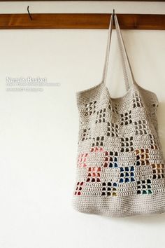 a crocheted bag hanging on a wall next to a coat rack with hooks