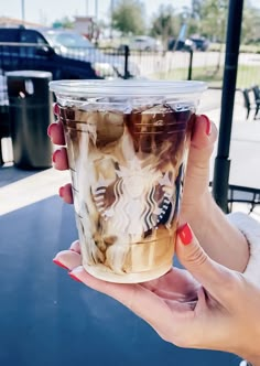 a woman holding up a starbucks cup in her hand