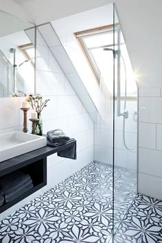 a white bathroom with black and white tile flooring in it's shower area