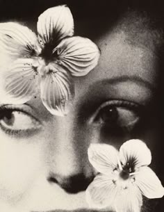 a black and white photo of a woman with flowers on her face