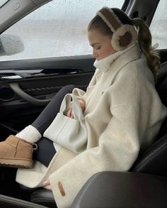 a woman sitting in the back seat of a car wearing headphones and holding a purse