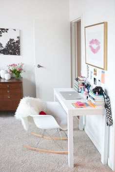 a white desk and chair in a room with pictures on the wall above it,