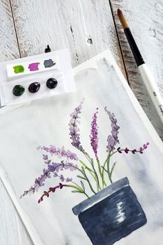 an art project with watercolors and paintbrushes on a white wooden surface