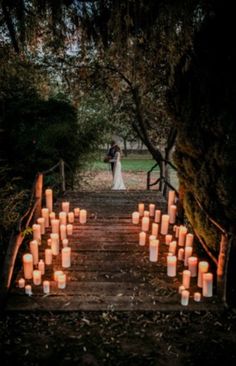 a bride and groom standing on a wooden bridge with candles in the shape of hearts