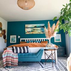 a bed room with a neatly made bed next to a plant and pictures on the wall