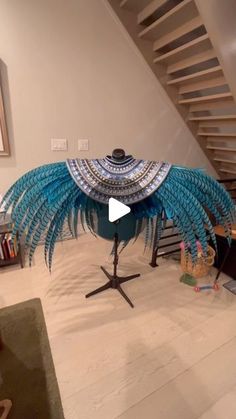 a large blue bird sculpture sitting on top of a wooden table next to a stair case