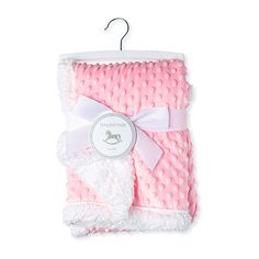 a pink and white baby blanket with a bow on the front hanging from a hook