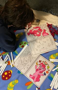 a young boy laying on top of a blue bed covered in lots of coloring paper