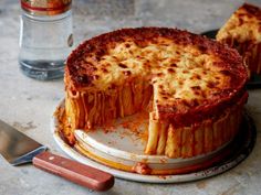 there is a large cheese cake on the plate with one slice missing from it and two knives next to it