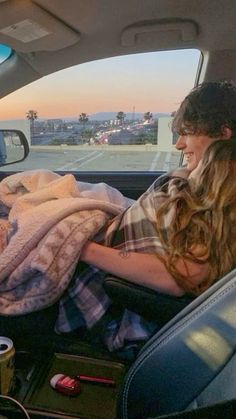 a woman sitting in the back seat of a car with blankets on top of her