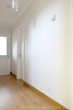 an empty room with white walls and wood floors is seen in this image from the hallway