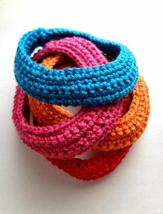 four crocheted bracelets are stacked on top of each other in different colors