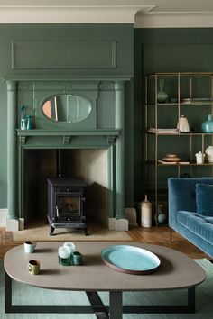 a living room with green walls and a wood burning stove in the centerpieces