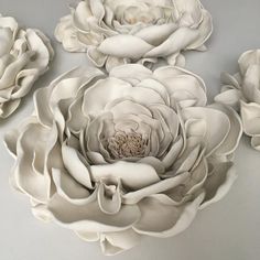 three large white flowers sitting on top of a table