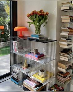 a bookshelf filled with lots of books next to a vase full of flowers