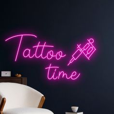 a neon sign that says tattoo time on the wall next to a chair and table