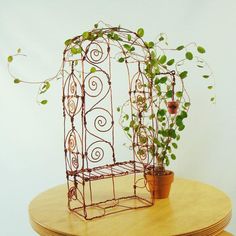 an iron birdcage sitting on top of a wooden table next to a potted plant