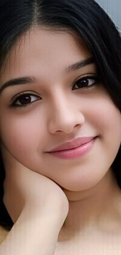 a woman with long black hair and brown eyes smiles at the camera while leaning on her elbow