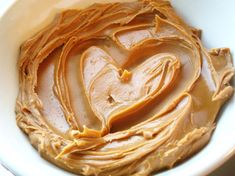 a white bowl filled with peanut butter in the shape of a heart on top of it