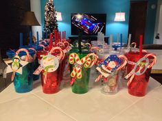 candy canes and candies are in plastic cups on a table with christmas decorations