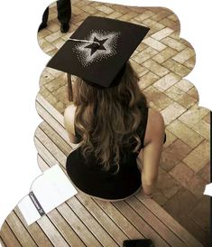 a woman sitting on top of a wooden bench wearing a graduation cap and holding a cell phone