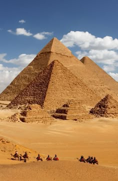 people riding camels in front of the pyramids