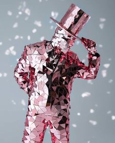 a man in a pink suit and top hat is holding a silver object up to his face