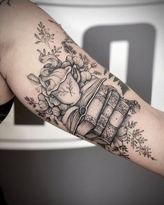 a woman's arm with a tattoo on it and flowers around the arm, in black and white