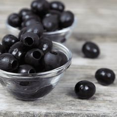 some black olives are in small glass bowls