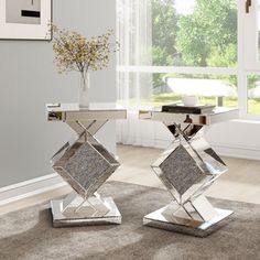 two silver tables sitting on top of a carpeted floor next to a vase filled with flowers