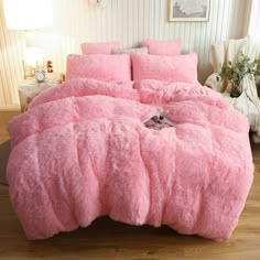 a bed with pink comforter and pillows in a room