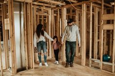 a man and woman holding hands while walking through a house under construction with their daughter