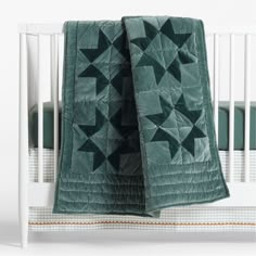 a crib bed with a green quilt on it